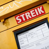 Die Gewerkschaft Verdi ruft zu Streiks bei der Post auf. An einem Briefkasten ist ein roter Aufkleber mit der Aufschrift "Streik" aufgeklebt.
