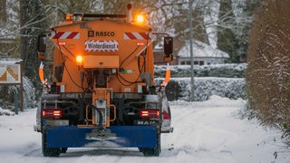 Ein Schneepflug räumt eine Straße.