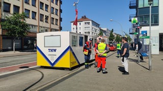 Helfer des Deutschen Roten Kreuzes stehen vor einem Container des THW in Bremerhaven