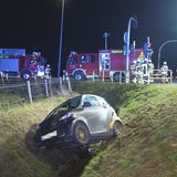 Ein Auto, das von der Straße abgekommen ist, liegt abseits einer Kreuzung in einem Graben.