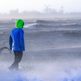 Ein Spaziergänger läuft bei Sturmflut und Wellen am Ufer der Wesermündung in Bremerhaven entlang.