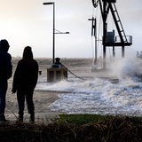 Spaziergänger laufen bei Sturmflut am Ufer der Wesermündung in Bremerhaven entlang.