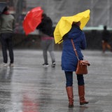Passanten schützen sich mit Regenschirmen vor starkem Wind (Archivbild)
