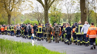 Einsatzkräfte der Feuerwehr und Soldaten der Bundeswehr gehen eine Straße im Landkreis Stade entlang. Der sechs Jahre alte Arian aus Elm wird weiter vermisst. Die Suche nach ihm geht weiter.