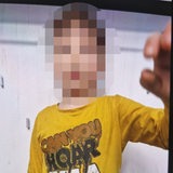 Ein kleiner Junge in gelbem Shirt schaut in eine Kamera