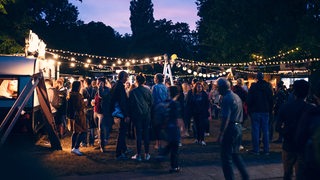 Besucher des Summer-Sounds-Festivals mit Lichterketten am Abend
