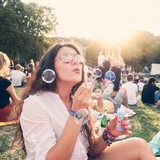 Junge Frau lässt Seifenblasen steigen auf dem Summer-Sounds-Festival