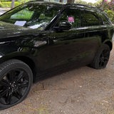 Ein schwarzer SUV hat platte Reifen und es klebt ein Sticker an der Fensterscheibe.