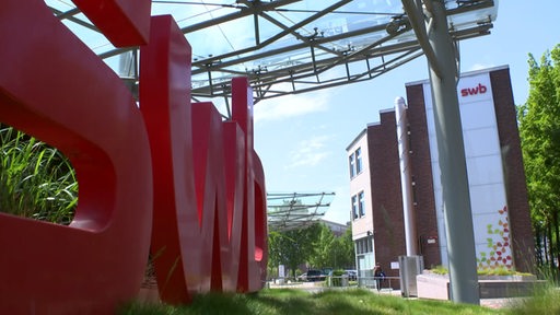 Das SWB-Logo in großen roten Buchstaben aufgestellt vor dem Firmengebäude.