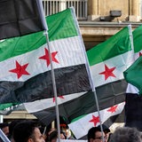 Männer halten syrische Flaggen hoch.