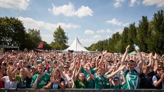 Werder-Fans jubeln beim Tach der Fans vor strahlendem Sonnenschein und blauem Himmel