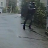 Ein maskierter Mann rennt durch eine Straße.