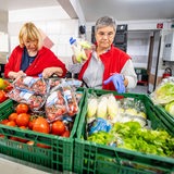 Drei Frauen sprtieren Lebensmittel bei der Tafel.