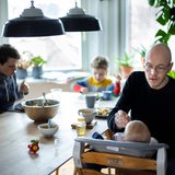 Eine Familie mit 2 Kindern sitzt gemeinsam beim Essen am Tisch.