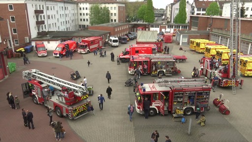 Von Oben sind auf einer Feuerwehrwache mehrere Feuerwehrautos zu sehen.