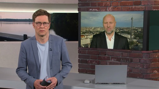 Der Moderator Felix Krömer im Studio von buten un binnen und auf dem Monitor der Reporter Olaf Sundermeyer.