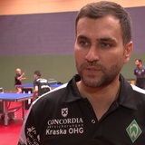 Cristian Tamas im Interview vor den Tischtennisspielern beim Training im Hintergrund.