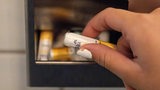 Eine Frau nimmt auf einer Toilette kostenlose Tampons aus einer Metallbox. 