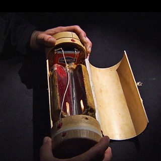 Modell der Paketbombe: eine aufgeklappte Papprolle, in der sich Sprengstoff befindet.