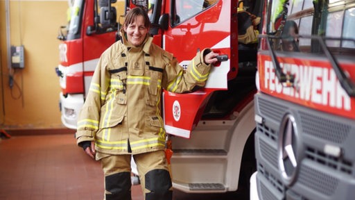 Feuerwehrfrau Tanja Schmitz steht an einem Einsatzfahrzeug