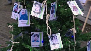 Bildern von gestorbenen Opfern im Iran am Tannenbaum vor dem Bremer Theater. 
