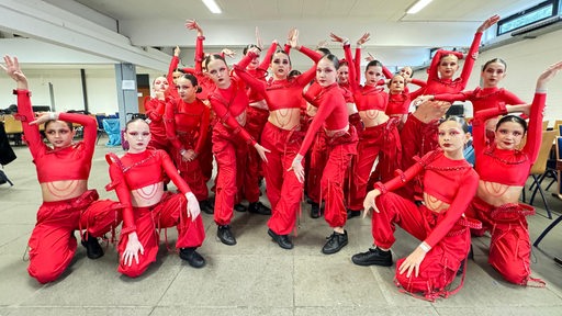 Tänzerinnen in roten Outfits posieren für die Kamera.