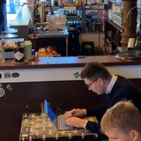 Ein Mann sitzt mit einem Laptop vor einer Bar
