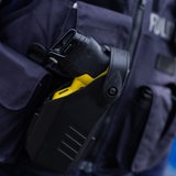 Ein Taser steckt im Holster einer Polizistin.