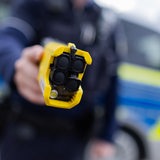 Ein Polizist hält einen Taser in Richtung Kamera.