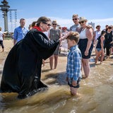 Ein Kind wird in der Weser getauft.