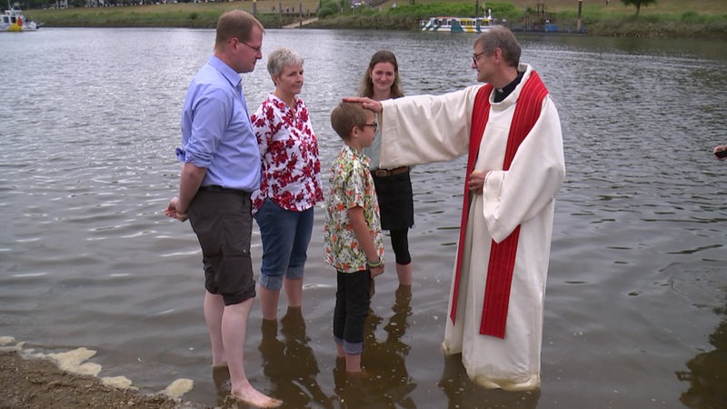 Menschen stehen in der Weser bei einer Taufe