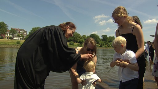 Ein Kind wird in der Weser getauft