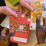 Ein junger Mann aus Afrika tauscht Gutscheine gegen Bargeld.