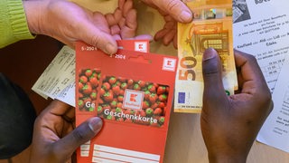 Ein junger Mann aus Afrika tauscht Gutscheine gegen Bargeld.