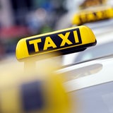 Taxi-Autos warten auf Fahrgäste. Zu sehen sind vor allem die Taxi-Schilder.