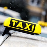 Gelbe Taxi-Schilder sind auf Autodächern zu sehen, es regnet.