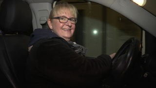 Die Taxifahrerin Bärbel Janßen sitz lächelnd in ihrem Taxi.