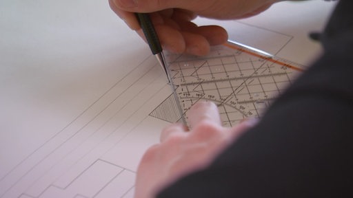 Eine Person zeichnet mit Bleistift und Geodreick eine Gebäudefassade