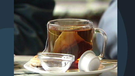 Zu sehen ist eine Tasse, welche mit Tee und einem Teebeutel gefüllt ist.