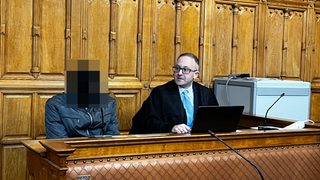 Angeklager Mann (verpixelt) sitzt neben seinem Verteidiger
