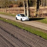Ein weißer Tesla fährt einen Feldweg entlang