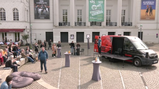 Auf dem Goethelatz vor dem Theater steht ein Wagen mit einer kleinen Bühne davor.
