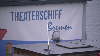 Auf einer Plane steht die Aufschrift "Theaterschiff Bremen". 