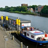 Ein Schiff liegt an einem Flussufer.