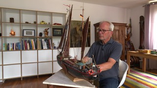 Der Bremer Thilo Wichmann mit einem aus Holz selbstgebauten Segelschiff.