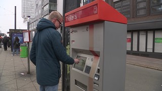 Eine Person ist dabei ein Ticket an einem Ticketautomaten der BSAG zu kaufen.