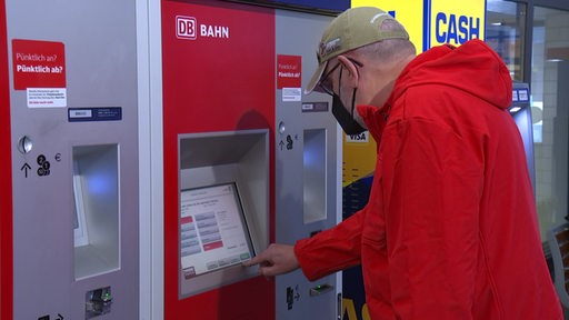 Ein Mann kauft an einem Ticketautomat der DB ein Ticket.