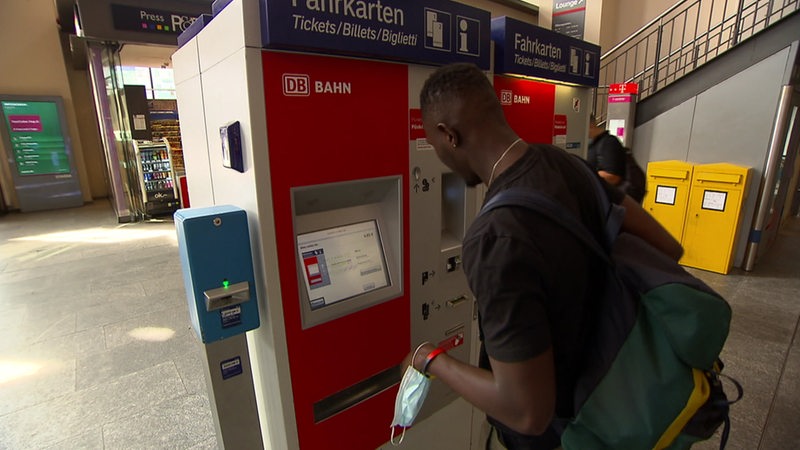 Ein Mann kauft ein Bahnticket an einem Fahrkartenautomat.