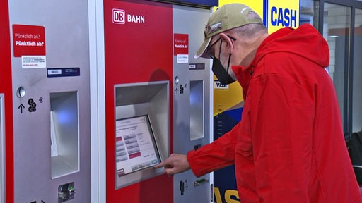 Ein Mann bedient einen Ticketautomat der Deutsche Bahn.