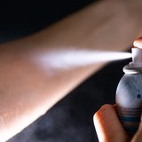 Deo aus einer Sprühdose wird auf die Haut eines Arms gesprüht. 